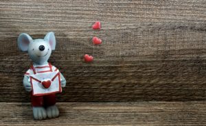 mouse figurine holding envelope and hearts